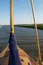 Travelling up a river from a moving sailing boat: foredeck and furled sails