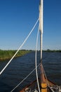 Travelling up a river from a moving sailing boat: foredeck and furled sails