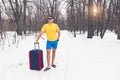 Travelling from winter to summer. Young man stands in summer clothers on the snow and dreams of vacation, sea, warm exotic country