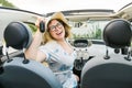 Travelling woman holding keys to new car and smiling at camera - ownership and purchase automobile concept