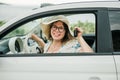 Travelling woman holding keys to new car and smiling at camera - ownership and purchase automobile concept