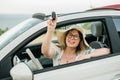 Travelling woman holding keys to new car and smiling at camera - ownership and purchase automobile concept