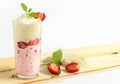 Strawberr banana milkshake in a glass glass decorated with mint leaves, kulubnik and whipped cream on a wooden table on a white ba Royalty Free Stock Photo