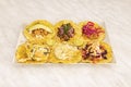 Tray of assorted tacos with corn tortillas, lots of melted cheese, purple onion, pulled pork, avocado, chicken tinga, nopales,