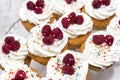 Tray with biscuit cakes with cream and raspberry berries, sweet
