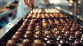 A tray of bonbons being drizzled with velvety chocolate ganache creating a beautiful symphony of flavors