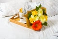 Tray with coffee, snack and bouquet of flowers on bed Royalty Free Stock Photo