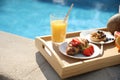 Tray with delicious breakfast near swimming pool, closeup Royalty Free Stock Photo