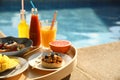 Tray with delicious breakfast near swimming pool, closeup. Space for text Royalty Free Stock Photo