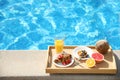 Tray with delicious breakfast near swimming pool. Space for text Royalty Free Stock Photo