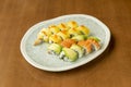 Tray of Different Flavor uramaki Sushi Topped with Norwegian Salmon, Mango Slices and Avocado Slices on Top