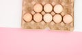 A tray of eggs on a white and pink background. eco tray with testicles. minimalistic trend, top view. Egg tray. Easter concept Royalty Free Stock Photo