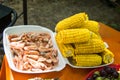 A tray is filled with corn and shrimp. Picnic outdoor
