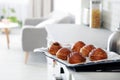 Tray with freshly oven baked buns on stove in kitchen.