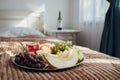 Tray of Fruit Lies on the Bed in Hotel Room, Bottle of Wine Stands on Background Royalty Free Stock Photo