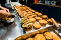 tray with many hamburger bun halves anointed with ketchup and mustard, served with cutlets and a slice of cheese