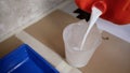 Tray of paint with primer. A worker pours primer into a measuring cup. Preparation for painting work. Primer canister Royalty Free Stock Photo