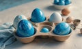 tray six blue and white Easter eggs, with few brown eggs, is arranged on white surface, accompanied by blue Royalty Free Stock Photo