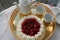 Gateau with strawberry and cream is waiting to be served together with a cup of strong coffee