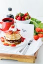 A tray table of breakfast items including pancakes, coffee and strawberries with a card and flowers for Mother`s Day.