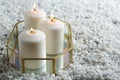 Tray with three white burning candles on rocks.