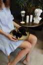 A tray of treasures in the hands of a young unrecognizable woman. A black hare and an octopus lie on a golden tray in