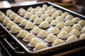 a tray of uncooked dumplings ready to be steamed