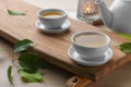 Tray with white cups of green tea, leaves and teapot on wooden table, closeup Royalty Free Stock Photo