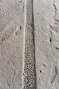 Tread marks on fresh snow. Track from car tire. Road covered with a thin layer of snow. Human footprints