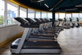 Treadmills hardly standing in front of large windows, gym, sports and fitness equipment