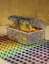 Treasure chest half open shows precious gold objects. Silver box sets on rhinestone base with gold background. Royalty Free Stock Photo