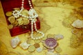 Treasure chest with jewelry and coins, compass and shells on vintage map