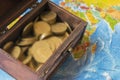 The treasure chest stands on a world map full of gold coins. Royalty Free Stock Photo