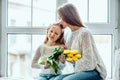 They treasure each other.Loving mother and daughter sitting on the window sill at home