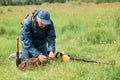 Treasure hunter holding ground in hands, looking for his finding, numismatist searching coins in meadow or field, man in cap and