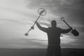 Treasure hunter with a metal detector on a beveled wheat field in search of adventure against the backlight of the sun