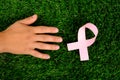 Treatment cancer, helping hand on green grass, pink ribbon symbol