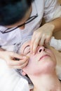 The treatment of the face in a spa by a female beautician. Extracting black dots or fat spots from a young woman`s skin