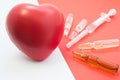 Treatment, support with medication and heart protection. Drugs - vials and syringe on red background aimed at heart, which lies ne