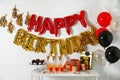 Treats and gifts on table in room decorated for birthday party with balloons Royalty Free Stock Photo