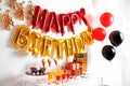 Treats and gifts on table in room decorated for birthday party with balloons Royalty Free Stock Photo