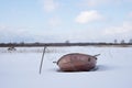 Tree and a boat stand on the shore of a snowy lake