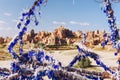 Tree branches hung with amulets from the evil eye by Nazars and a view of the rocky cave city. Cappadocia Turkey.