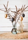 Tree branches in vase with black and bronze colored Easter eggs hanging on string, white rustic wood board background. Royalty Free Stock Photo