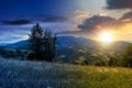 Day and night time change concept above scenic summer landscape with meadow in mountains.