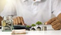 Tree growing on a pile of money and businessman holding coins in hand