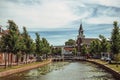 Tree-lined canal with bascule bridge, church and brick houses in street on the banks on sunny day in Weesp.