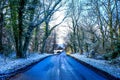 A tree lined country lane going downhill, aspalt patches on the Royalty Free Stock Photo