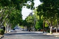 Tree lined street in residential neighborhood with cars parked in front of houses. School crossing sign Royalty Free Stock Photo