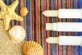 Tree lip balms, sunscreen sticks on the colorful beach towel wirh sand and seashells. Summer lip treatment and UV protection